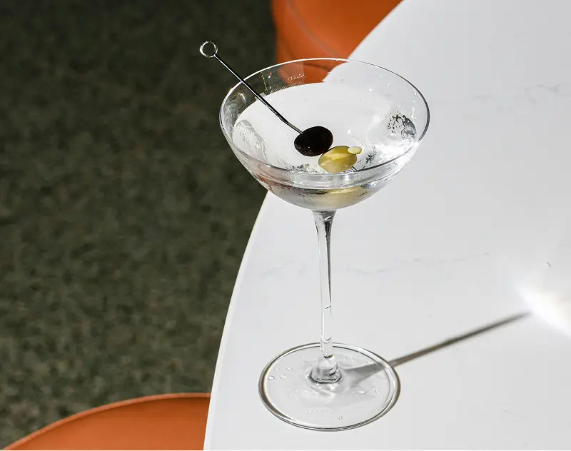 Martini cocktail with olives on a table inside a lounge setting