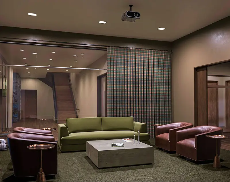 Modern lounge seating area with couches, chairs, and projector inside the clubhouse