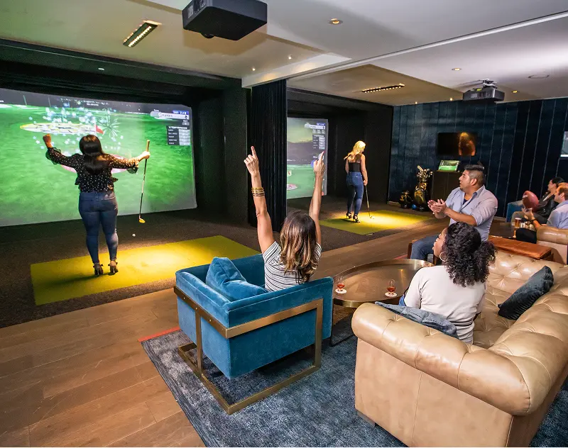 Group enjoying an indoor golf simulator game inside a lounge setting