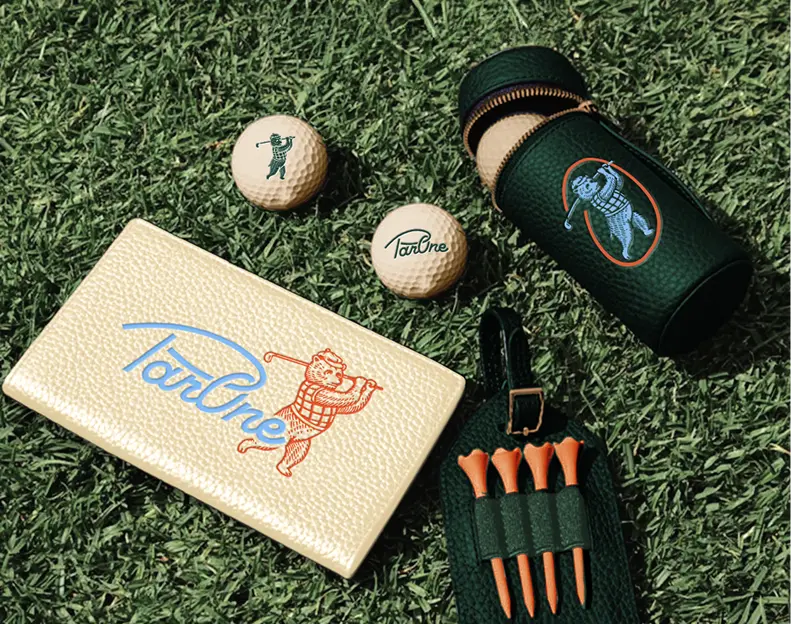 Golf accessories including golf balls, tees, and branded merchandise on artificial turf