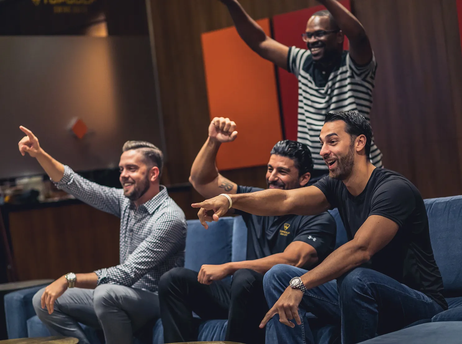 Group of friends cheering and watching a game inside a clubhouse lounge