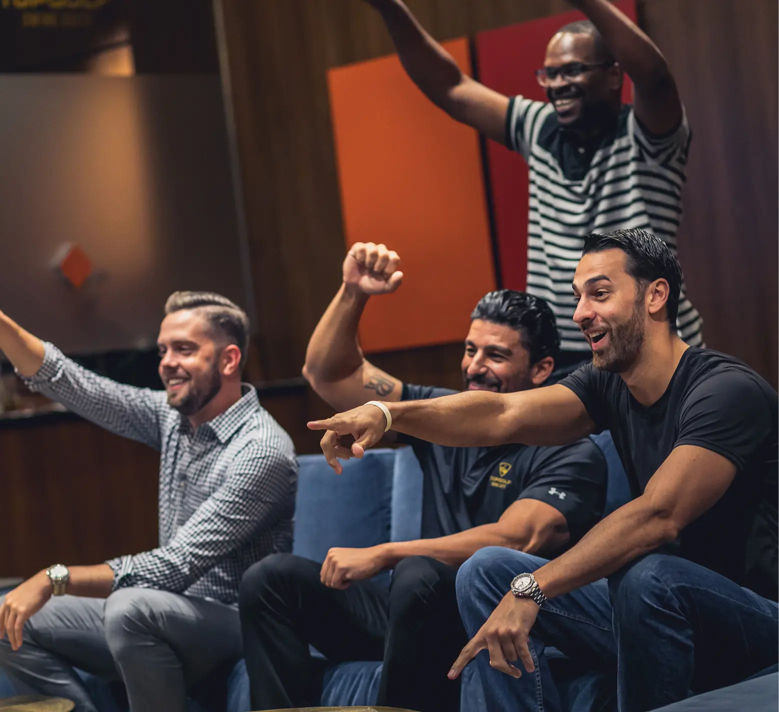 Group of friends cheering and watching a game inside a clubhouse lounge