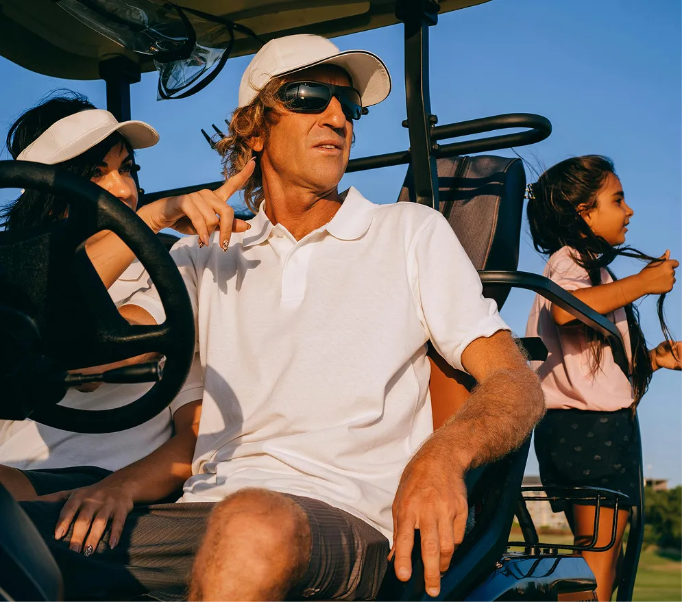 People riding in a golf cart at the golf course during sunset