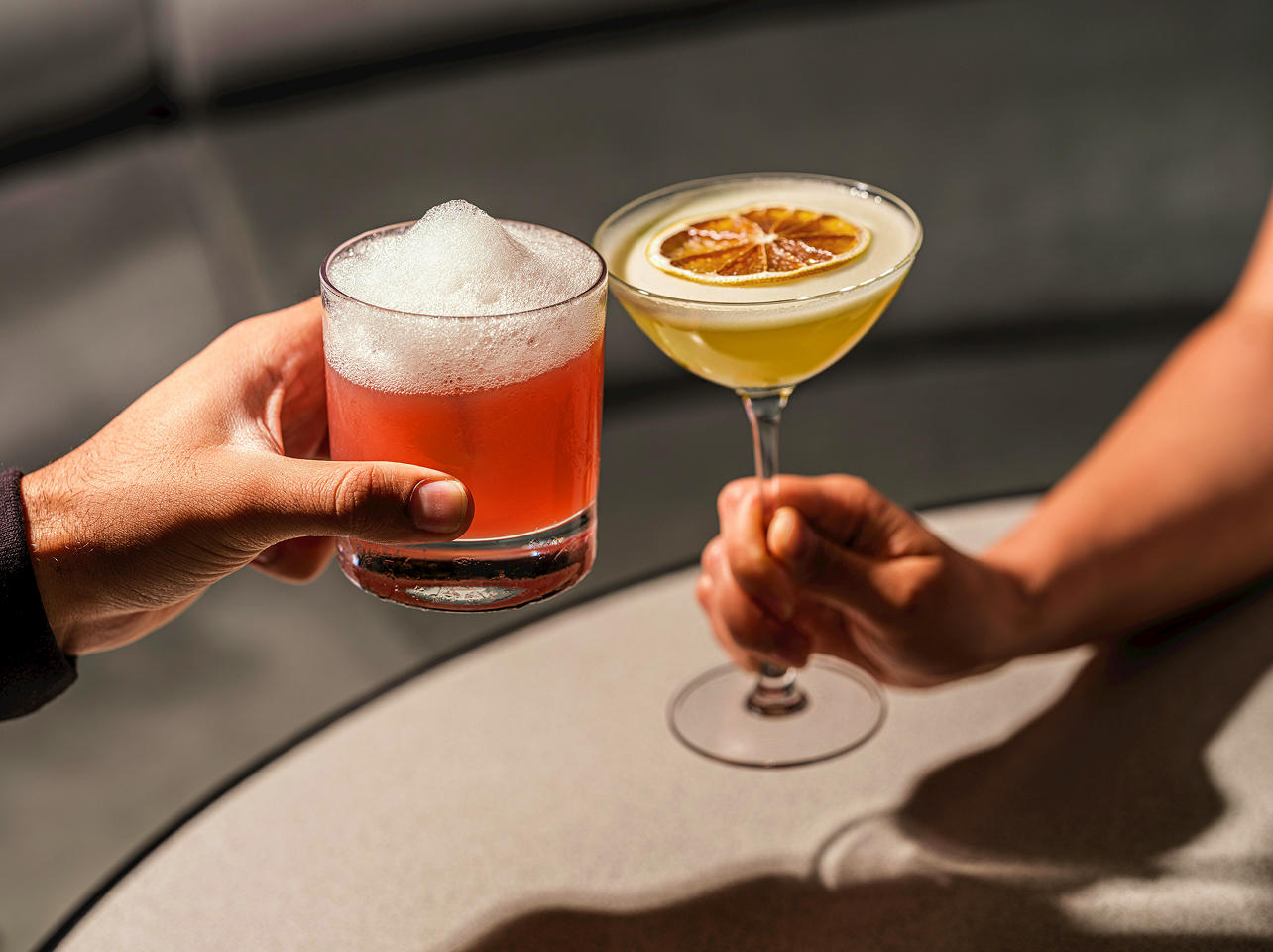 Two people holding cocktails at a lounge table inside the clubhouse
